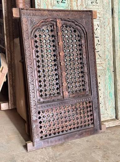 Hand-carved jharokha-style wooden door with jali lattice