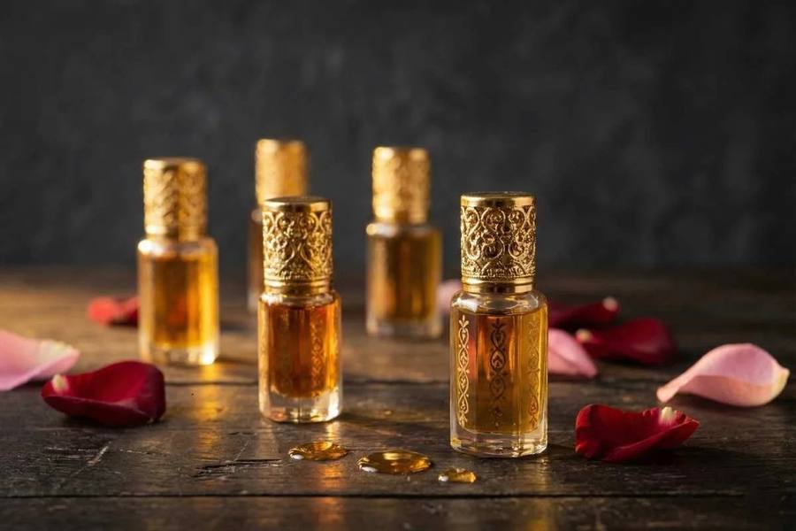 Gold-capped glass attar perfume oil bottles with rose petals