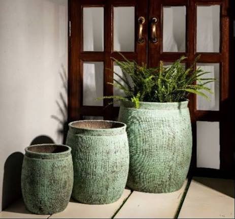 Glazed green terracotta planters by a wooden doorway