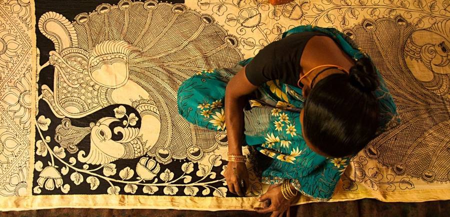 Artisan hand-painting a Kalamkari peacock textile