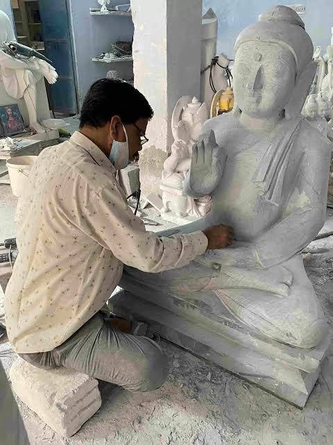 Artisan hand-carving a large marble statue in a workshop