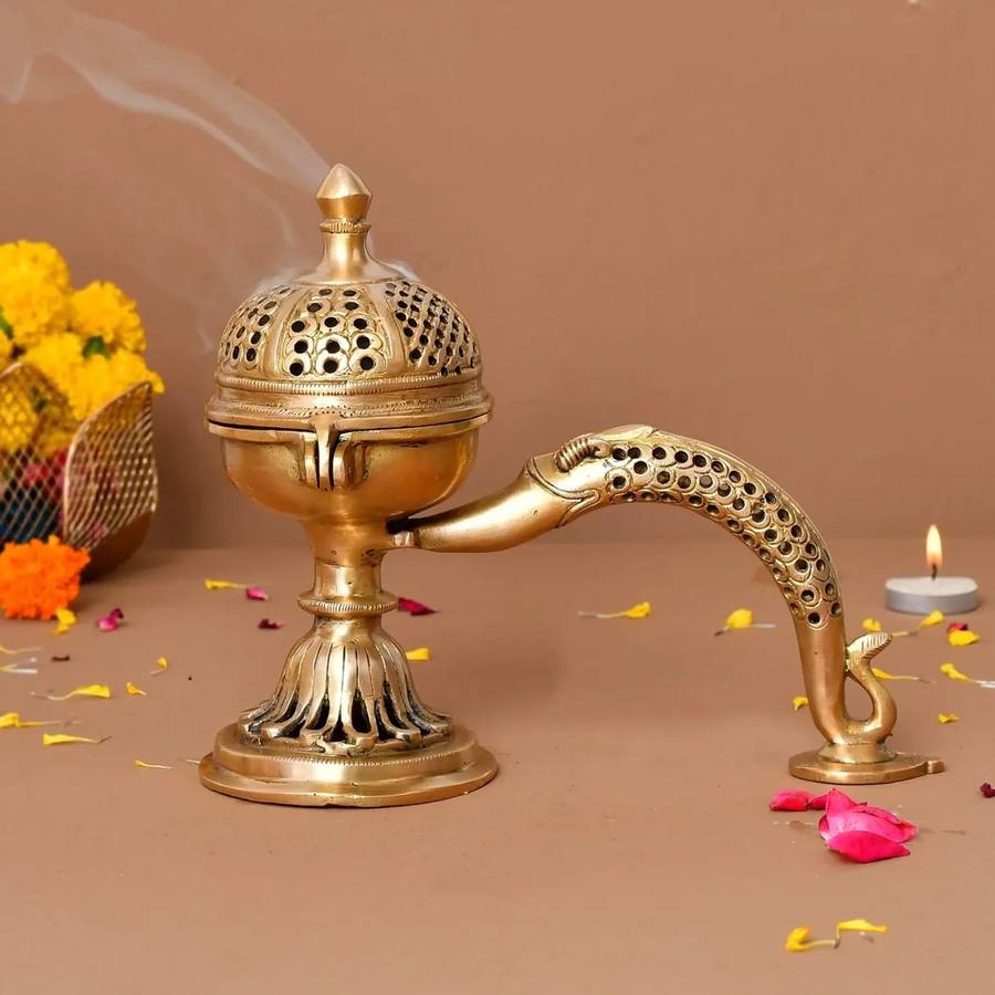 Brass peacock-design incense burner with marigold petals