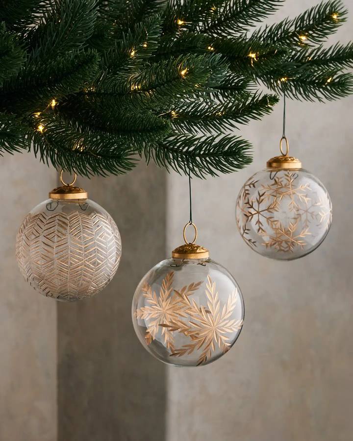 Hand-blown glass Christmas ornaments with gold snowflake designs on a tree