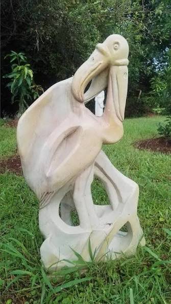 Carved soapstone pelican bird sculpture in a garden